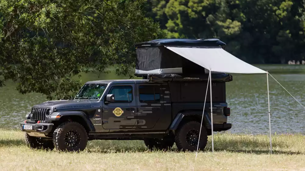 Frontier awning mounted on the open James Baroud Odyssey, with a beach in the background.
