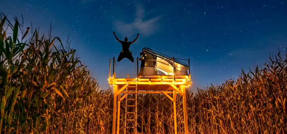 A night shot of the Dachzeltnomaden rooftop tent village, with Dennis under a starry sky