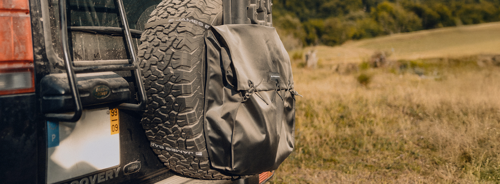 Rear view of a Land Rover featuring the James Baroud Waste Bag securely attached to the spare tire.