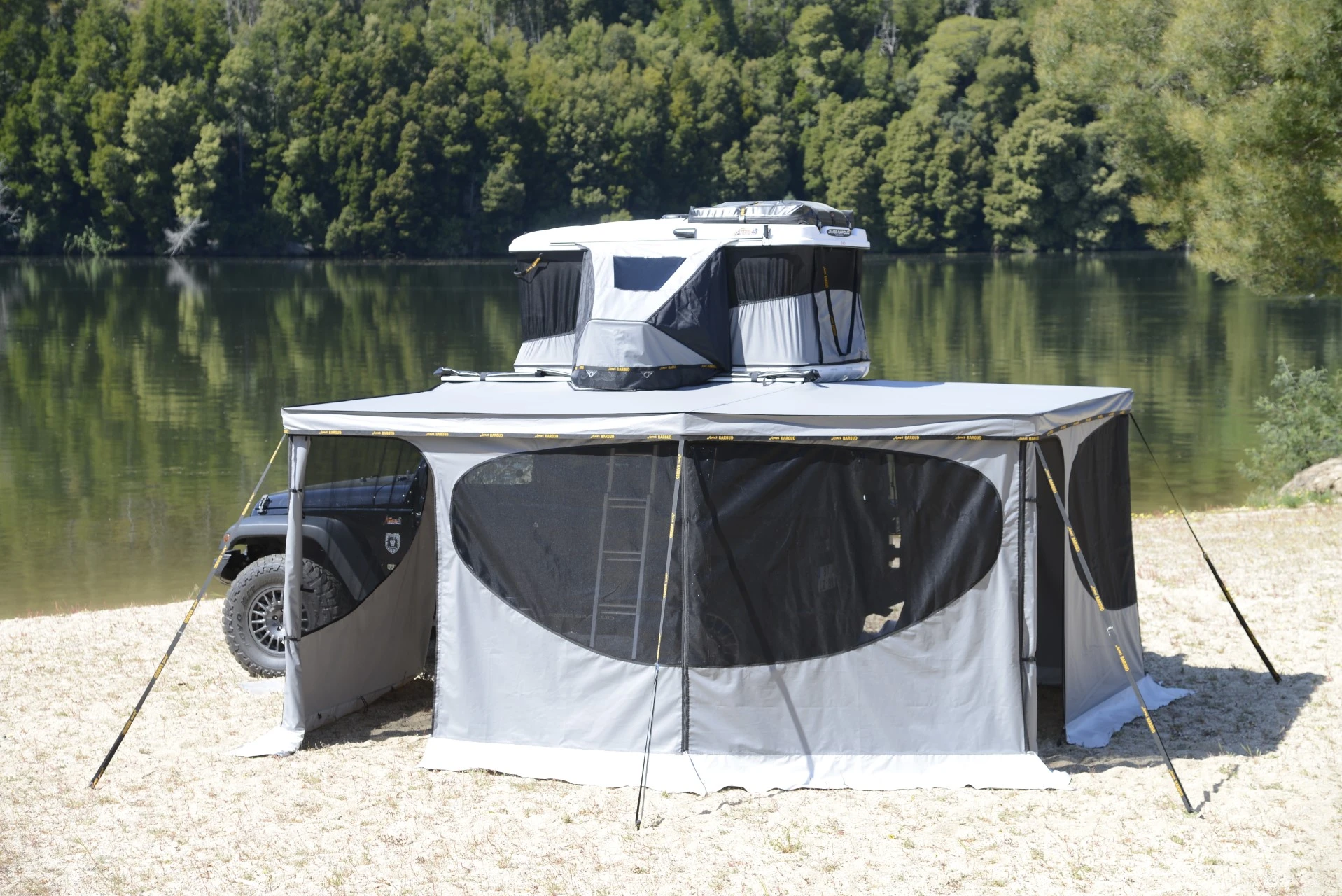 A car with a rooftop tent and acar awning  parked by the lake