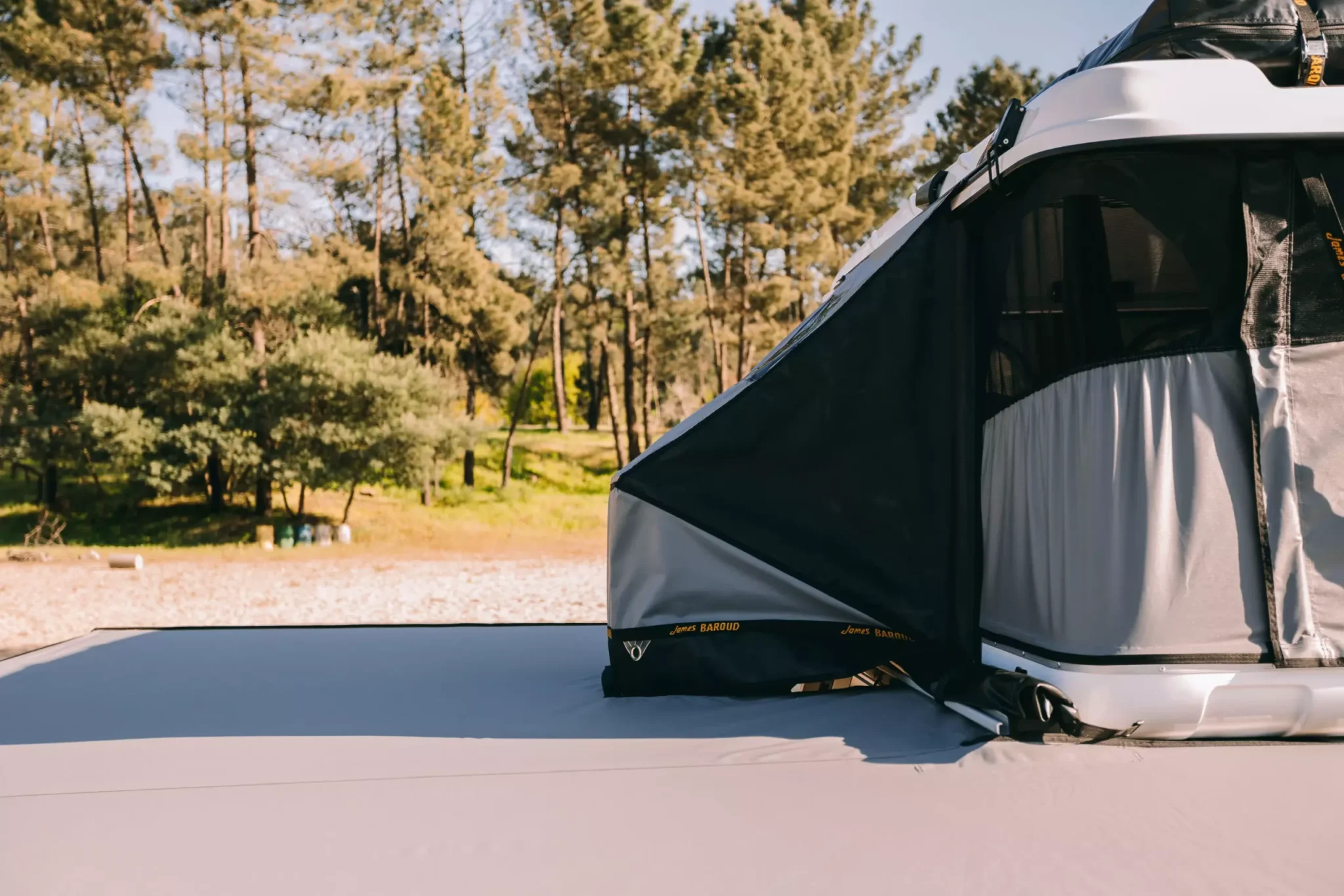 An awning with a rooftop tent on the forest, a  james baroud evolution tunnel connects both