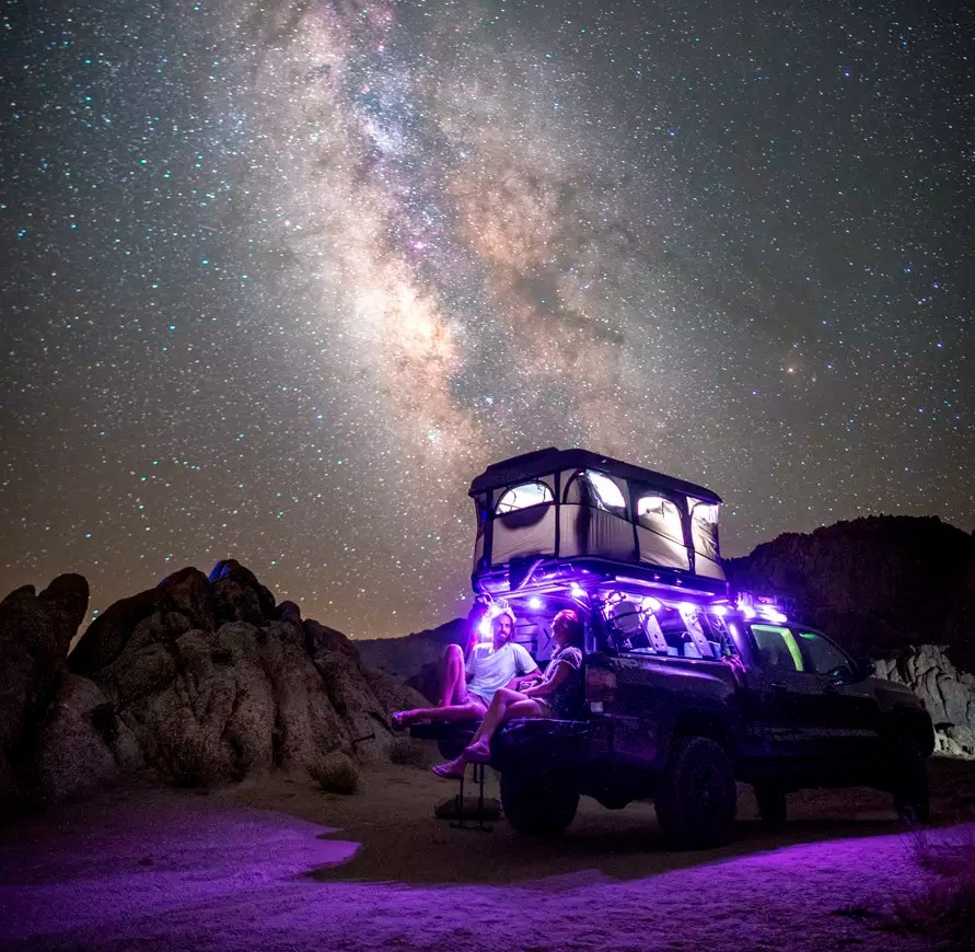 A car with a rooftop tent and acar awning parked by the lake