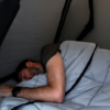 Person sleeping inside a rooftop tent using the James Baroud TBS bedding system